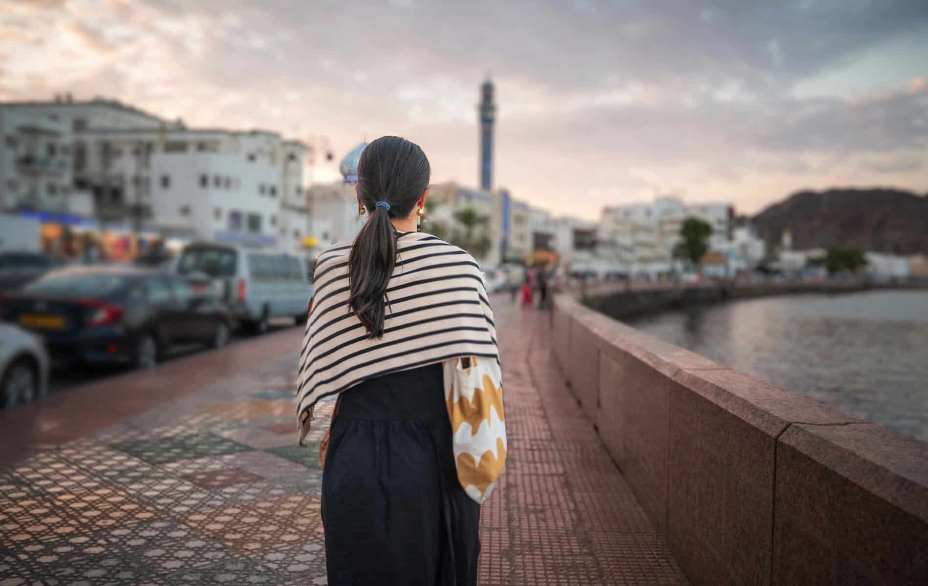 A woman walking alone along the Corniche in Matrah, Muscat.