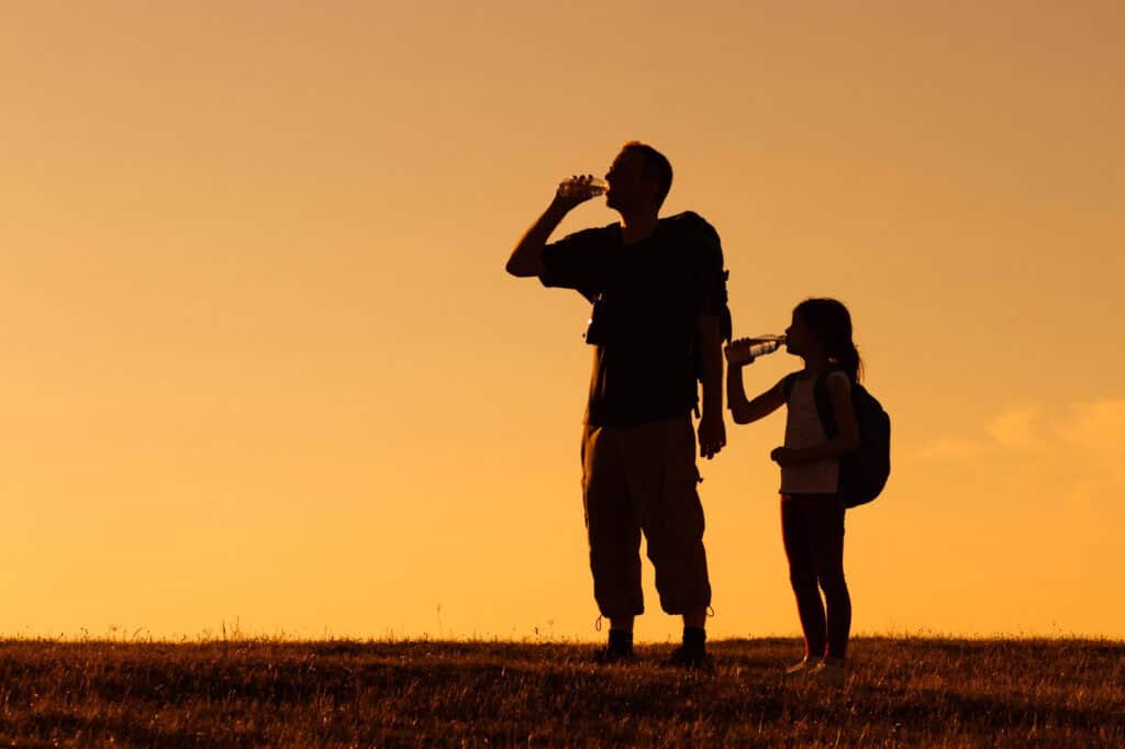 A father and his daughter drinking water in the desert