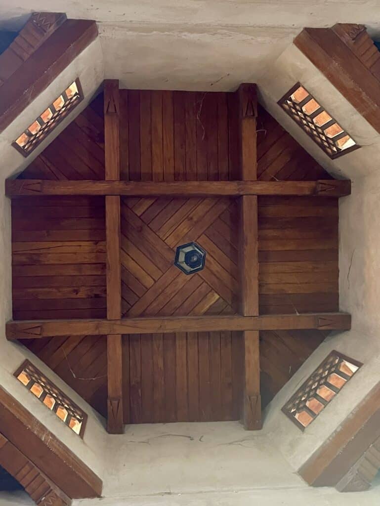 Traditional wooden ceiling with angled ventilation windows inside the West Souq in Nizwa, showing the old cooling system used in Omani architecture.