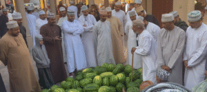 Men gathered around a pile of watermelons at Nizwa Souq in Oman during the Friday market