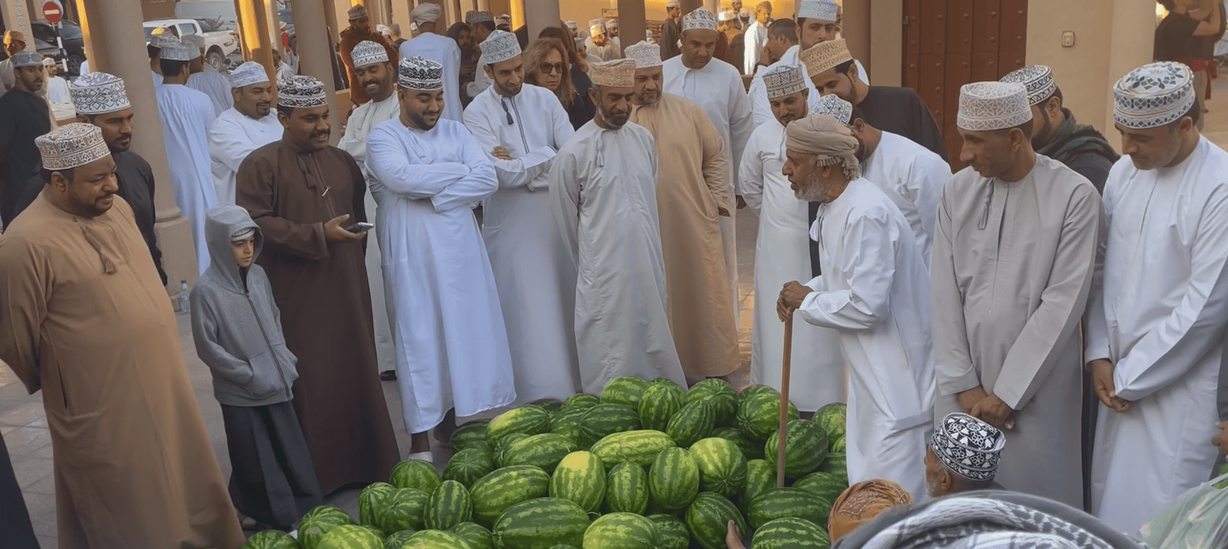 Men gathered around a pile of watermelons at Nizwa Souq in Oman during the Friday market