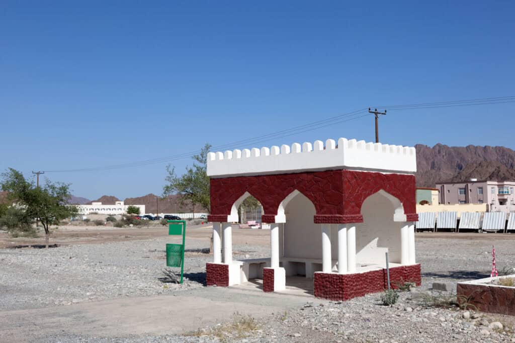 Traditional Omani bus stop with arched architecture and red-and-white stonework