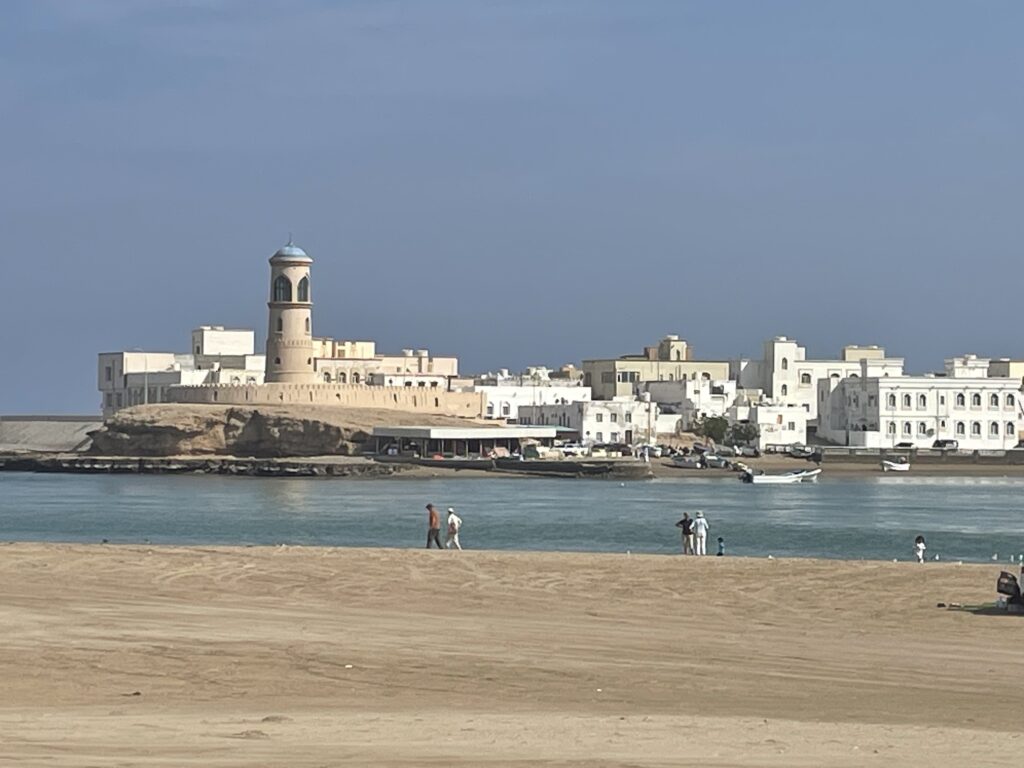 Coastal view of Sur, Oman, with the lighthouse and old town seen from the beach, highlighting the best things to do in Sur.